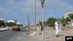 Un piéton passe devant un feu de signalisation brisé dans une rue de Dakar le 3 juin 2023, suite aux violences meurtrières dans la capitale sénégalaise (Photo by Seyllou / AFP)