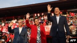 Thai candidates for prime minister Paetongtarn Shinawatra (C), Srettha Thavisin (R) and Chaikasem Nitisiri (L) wave during a rally for Thailand's main opposition Pheu Thai party at the Thunder Dome Stadium north of Bangkok, April 5, 2023.