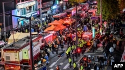 Onlookers, police and paramedics gather where dozens of people suffered cardiac arrest, in the popular nightlife district of Itaewon in Seoul on Oct. 30, 2022. 