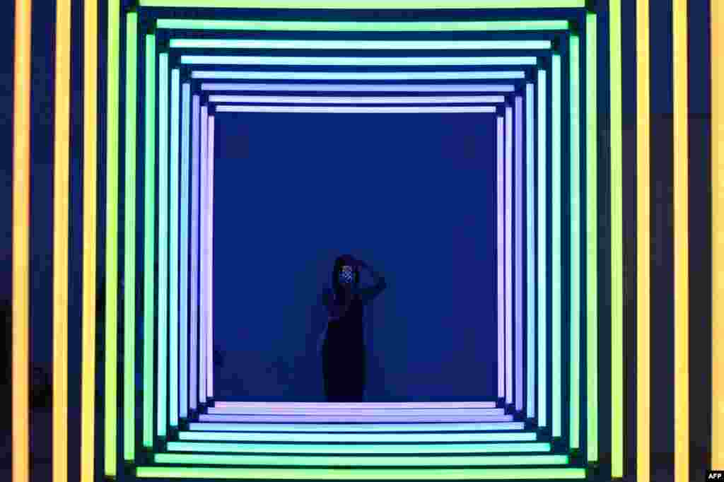 A woman uses her mobile phone to take a picture of Spectrum by Olivier Ratsi as she visits an exhibition at a museum in Beijing.