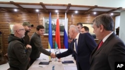 Ukrainian and Russian delegations greet each other prior to the Russian-Ukrainian talks in the Belavezhskaya Pushcha National Park, close to the Polish-Belarusian border, northward from Brest, Belarus, March 3, 2022.