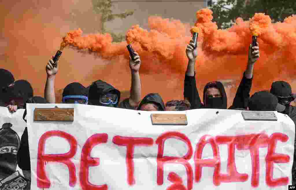 Protesters hold smoke bombs and a banner reading &quot;retirement at 20&quot; as they take part in the traditional May Day rally in Nantes, western France.