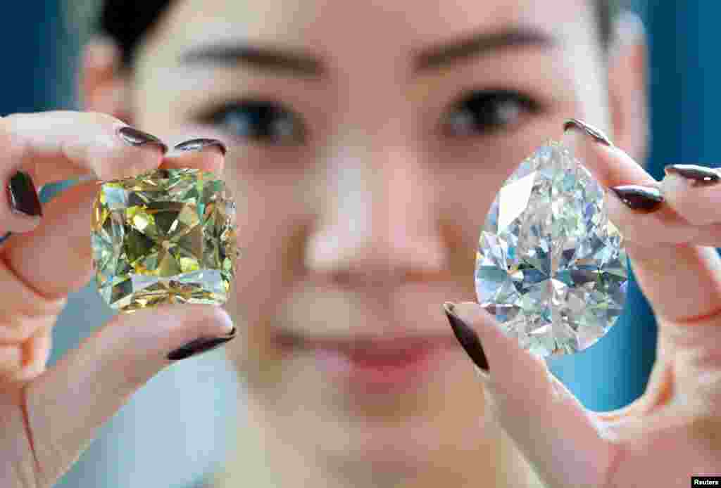 Returning for the third time since its mining in 1901, the &quot;Red Cross&quot; &mdash; a fancy intense yellow, cushion-shaped 205.07 carat diamond &mdash; and a 228.31 carat white diamond called &quot;The Rock&quot; that could fetch $30 million and is the largest ever seen throughout auction market history are pictured during a preview at Christie&#39;s before their auction sale in Geneva, Switzerland.