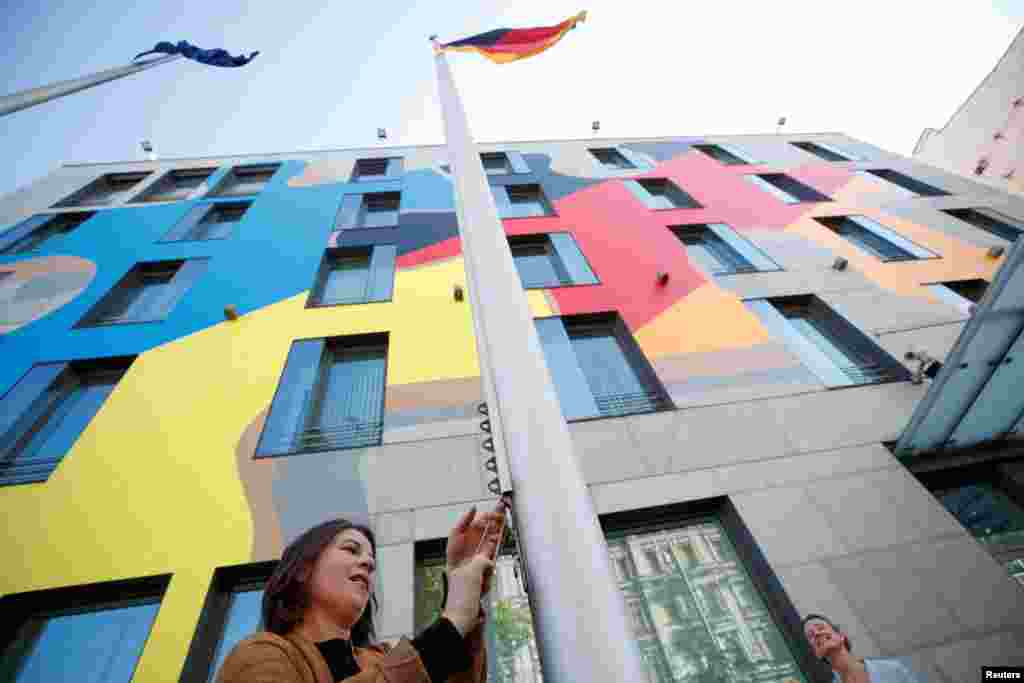 German Foreign Minister Annalena Baerbock raises the national flag outside the German embassy, as it reopens while Russia's attack on Ukraine continues, in Kyiv, Ukraine.
