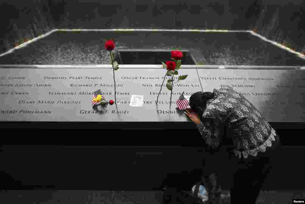 A woman grieves at the site of her husband&#39;s inscribed name at the edge of the North Pool during memorial observances on the 13th anniversary of the 911 attacks at the site of the World Trade Center in New York, Sept. 11, 2014.