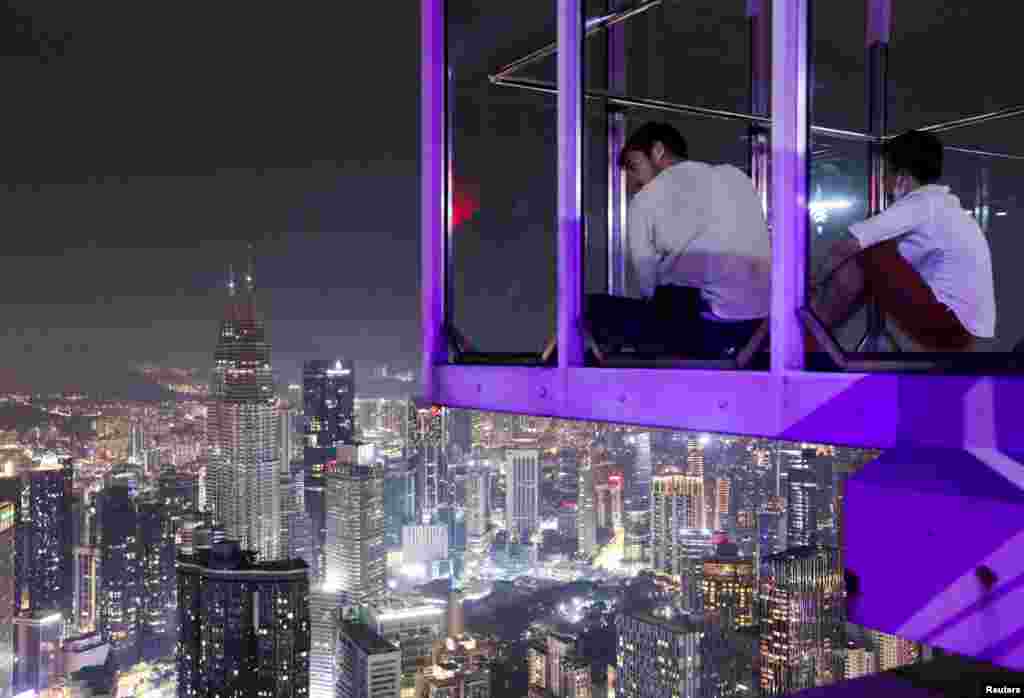 Visitors of the Kuala Lumpur Tower look at the skyline, including Malaysia&#39;s landmark Petronas Twin Towers, after the lights were turned off to mark Earth Hour, in Kuala Lumpur.