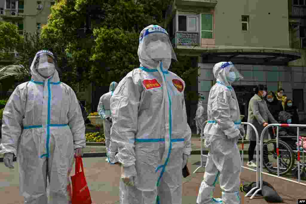 Workers and volunteers look on in a compound where residents are tested for the COVID-19 coronavirus during the second stage of a pandemic lockdown in Jing&#39; an district in Shanghai.