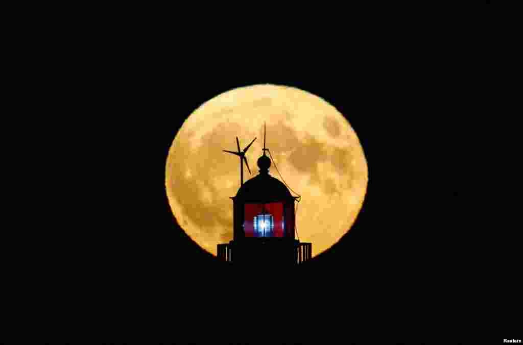 A full moon, known as &quot;Buck Moon,&quot; is seen behind a lighthouse in Saint-Nazaire, France, July 13, 2022.