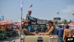 Taliban fighters on a pickup truck move around a market area, flocked with local Afghan people at the Kote Sangi area of Kabul, August 17, 2021.