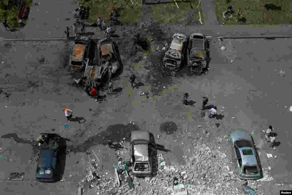 People check cars destroyed by a Russian missile strike at a residential area in Kharkiv, Ukraine.