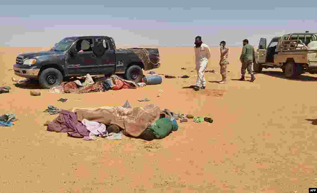 A handout picture provided by the Libya Ambulance Service shows rescuers recovering bodies of migrants found in the Libyan desert, in the southeastern region of Kufra near the border with Chad.&nbsp;Twenty people were found dead in the desert following a vehicle breakdown near the border with Chad.