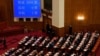 在北京人民大会堂举行的全国人民代表大会闭幕会议上，代表们在屏幕旁鼓掌，屏幕上显示了支持赋予亲北京的委员会权力以任命更多香港立法会议员的投票数。(2021年3月11日)