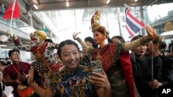 นักท่องเที่ยวจีนถ่ายรูปกับหุ่นละครเล็ก ที่สนามบินสุวรรณภูมิ เมื่อ 25 กันยายน 2023 (ที่มา: AP)