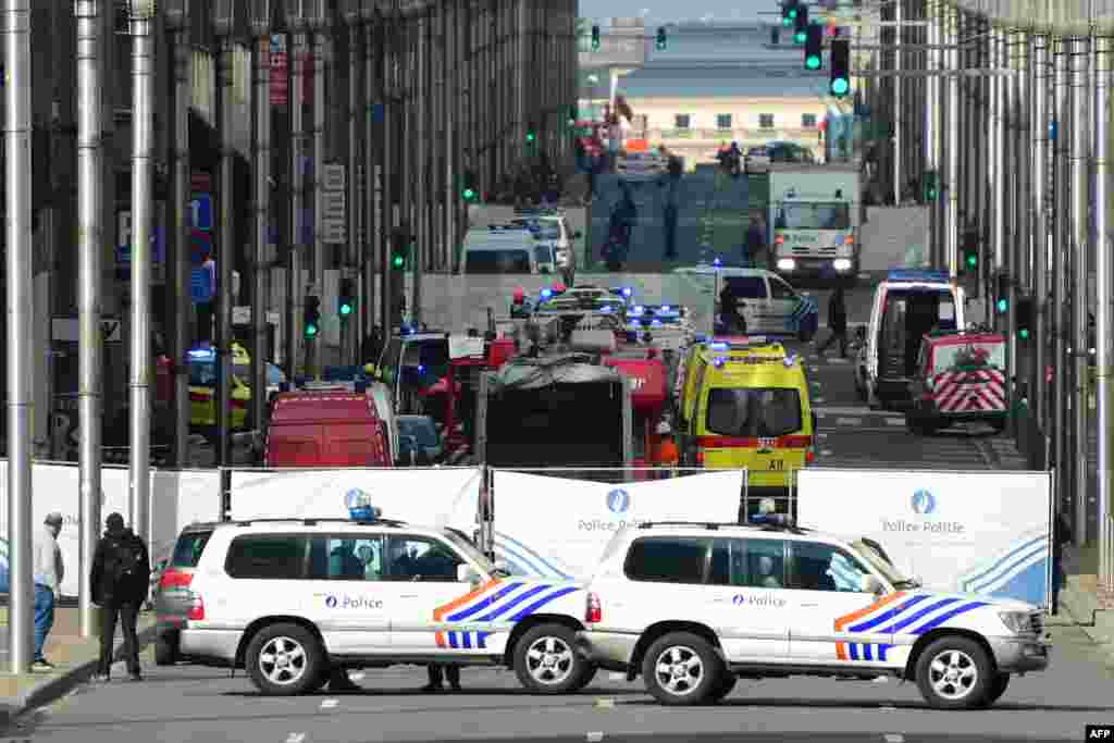 Policemen stand guard at the entrance of a security perimeter set near Maalbeek metro station, on March 22, 2016 in Brussels, after a blast at this station near the EU institutions caused deaths and injuries. 