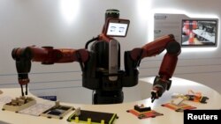 FILE - A Baxter robot of Rethink Robotics picks up a business card as it performs during a display at the World Economic Forum (WEF), in China's port city Dalian, Liaoning province, China onSept. 9, 2015. 