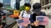 兩名香港市民7月4日美國獨立日手持A4紙印的美國國旗到美國領事館附近慶祝。(美國之音 湯惠芸拍攝)