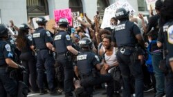 A man screams with emotion as he sees a policeman take a knee