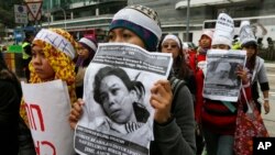 Domestic helpers and their supporters hold pictures of 23-year-old Indonesian maid Erwiana 