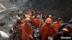 Members of National Disaster Response Force (NDRF) carry the body of a victim after recovering it from the debris during a rescue operation outside a tunnel after a part of a glacier broke away, in Tapovan in the northern state of Uttarakhand, India, Febr