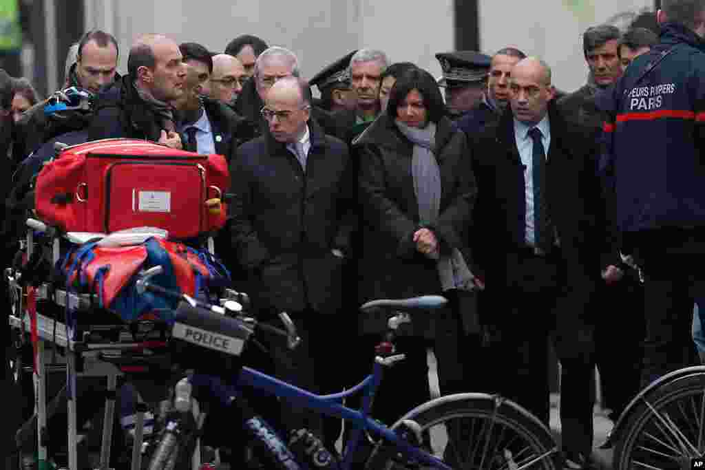 French Interior Minister Bernard Cazeneuve, center left, and Paris Mayor Anne Hidalgo, center right, arrive at the French satirical newspaper Charlie Hebdo&#39;s office, in Paris, Jan. 7, 2015.