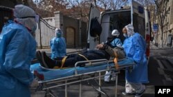 Medical staff in protective clothes are seen carrying a patient from an apartment suspected of having the virus in Wuhan, in Hubei province on January 30, 2020.