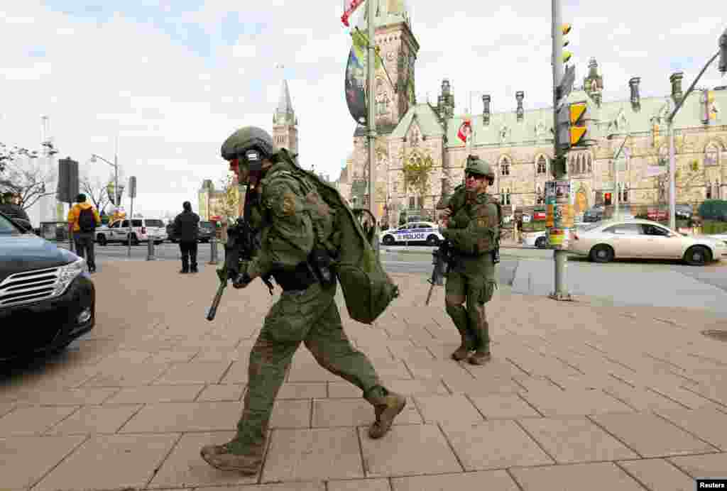 Armed RCMP officers head towards the Langevin Block on Parliament Hill following a shooting incident in Ottawa.