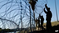 FILE - Members of the U.S. military install multiple tiers of concertina wire along the banks of the Rio Grande near the Juarez-Lincoln Bridge at the U.S.-Mexico border in Laredo, Texas, Nov. 16, 2018. 