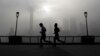People jog past the Pudong Financial District shrouded with fog and pollution at the Shanghai Bund in Shanghai, China, April 14, 2016. 