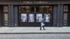 A man wearing a face mask to protect against the coronavirus walks past a closed Dolce & Gabbana store, Thursday, May 7, 2020, in the Soho neighborhood of Manhattan in New York. Nearly 3.2 million laid-off workers applied for unemployment benefits…