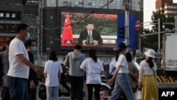 北京街头的行人观看电子屏幕上中国国家主席习近平。（2020年5月18日）