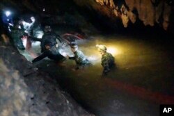 In this handout photo released by Tham Luang Rescue Operation Center, Thai rescue teams walk inside a cave complex where 12 boys and their soccer coach went missing, in Mae Sai, Chiang Rai province, in northern Thailand, July 2, 2018. All were found alive Monday.