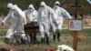 俄罗斯圣彼得堡的丧葬业人员身穿防护服掩埋新冠病毒死者，死者的亲友远远地遥望他们的亲人在新冠患者死去后被指定的区域下葬。（2020年5月15日）