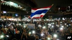 ผู้ชุมนุมรายหนึ่งโบกธงชาติไทย และถือป้ายข้อความ ขณะร่วมประท้วงเมื่อวันที่ 18 ตุลาคม 2020 ที่กรุงเทพมหานคร (ที่มา: เอพี)