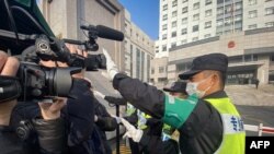 资料照片：一名警察挡住记者的镜头阻止拍摄审讯公民记者张展的上海浦东新区法院外景。（2021年12月28日）