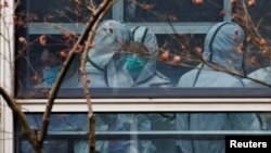 Members of the World Health Organization (WHO) team, tasked with investigating the origins of the coronavirus disease (COVID-19), don personal protection suits during a visit at the Hubei Animal Epidemic Disease Prevention and Control Center in Wuhan, Hub