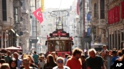 FILE - People walk in central Istanbul's Istiklal Avenue, the main shopping road of Istanbul, in this photo dated Wednesday, Aug. 22, 2018. Tourists have returned in droves to Turkey, helped this summer by the sharp fall in the value of the Turkish lira following economic uncertainty and a rift with the United States.
