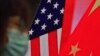 资料照片：中国外长王毅在外交部举行的“蓝厅论坛”上就中美关系发表演讲时，一名戴口罩的妇女坐在显示美中国旗的屏幕边。(2021年2月22日)