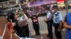 香港警察在维多利亚公园外拦截一名妇女，她身穿纪念六四的T恤，做出反送中运动“五大诉求 缺一不可”的手势。（2021年6月4日）