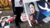 4月11日，韩国一名抗议者举着一个印着朝鲜领导人金正恩肖像的横幅，而地上是另一幅印着韩国总统朴槿惠肖像的横幅