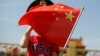 一名站在北京天安门广场的小男孩身穿美国T恤手拿中国国旗。（2019年5月7日）