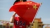 一名站在北京天安门广场的小男孩身穿美国T恤手拿中国国旗。（2019年5月7日）