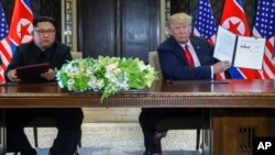 U.S. President Donald Trump holds up the document that he and North Korea leader Kim Jong Un had signed at the Capella resort on Sentosa Island, June 12, 2018, in Singapore. The most tangible outcome of their summit appeared to be a commitment to recover 