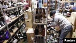 A worker cleans up broken bottles at a liquor shop after a strong quake in Fukushima, Japan, Feb. 13, 2021, in this photo taken by Kyodo.