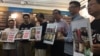 香港支联会2017年2月手举张隽勇、罗富誉和陈兵等人的照片接受陶君行从美国带回的“铭记八酒六四”纪念酒。