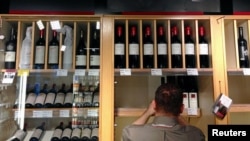 FILE - Bottles of Penfolds Grange, made by Australian wine maker Penfolds and owned by Australia's Treasury Wine Estates, are displayed as a shop assistant places more wine bottles onto shelves below at a wine shop in central Sydney, Australia, Aug. 