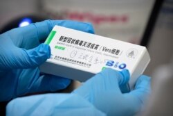 FILE - A medical worker holds a package for a Sinopharm vaccine at a vaccination facility in Beijing, Jan. 15, 2021.